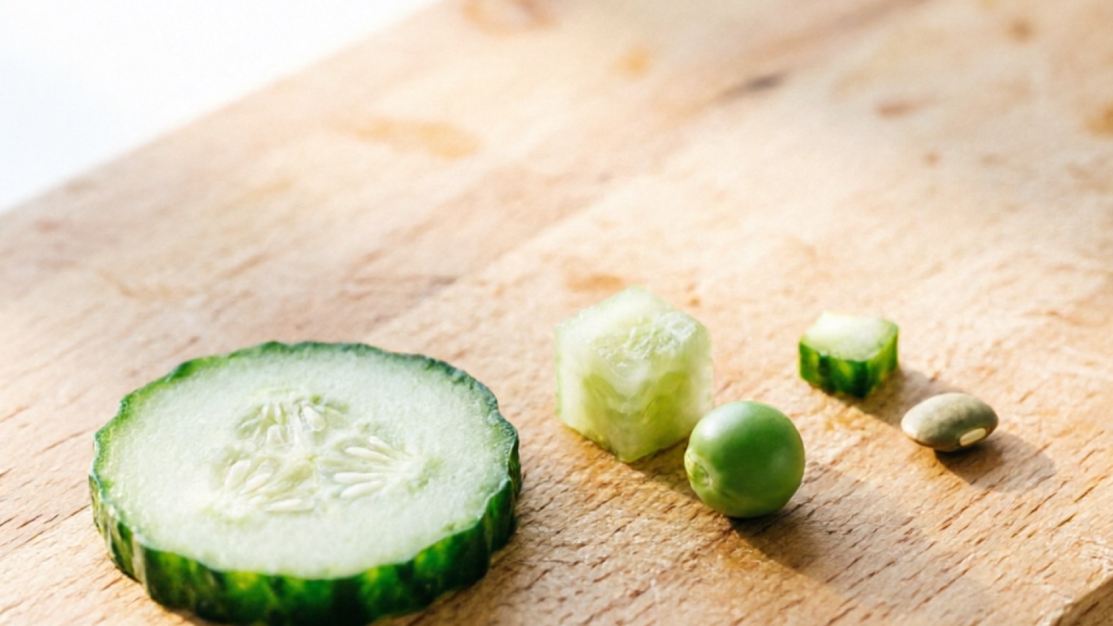 Cucumber slices of different sizes arranged for hamster portion comparison, with a pea for scale